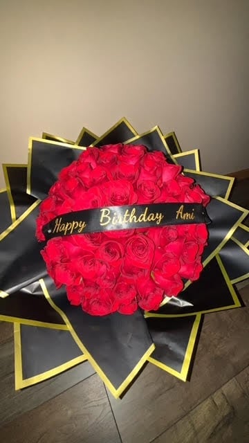 Large arrangement of red roses with Happy Birthday ribbon on black and gold star-shaped backdrop