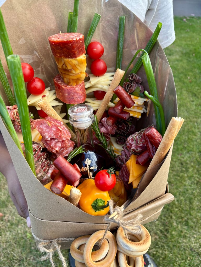 Gourmet charcuterie bouquet wrapped in kraft paper containing cured meats, cheeses, vegetables, and crackers with green onions and wooden handles
